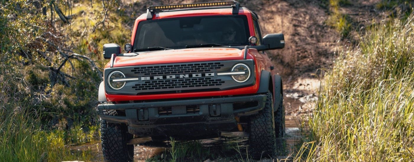 A red 2021 Ford Bronco off-roading on a trail
