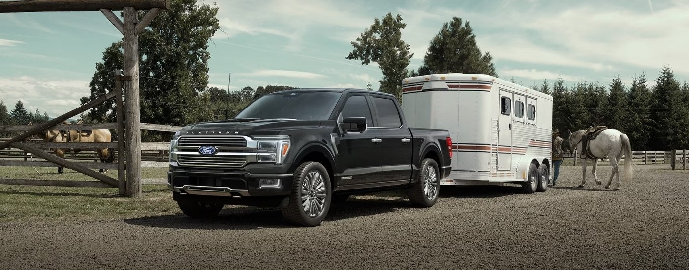A black 2025 Ford F-150 Platinum towing a trailer.