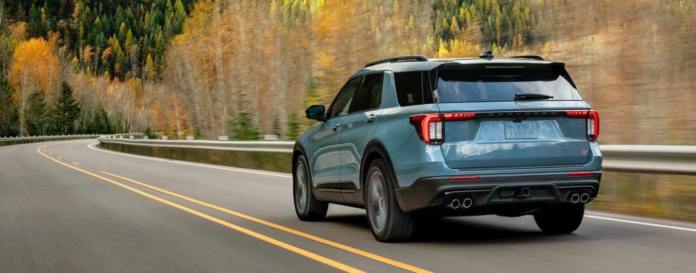 Blue 2026 Ford Explorer rear view driving on a paved road.