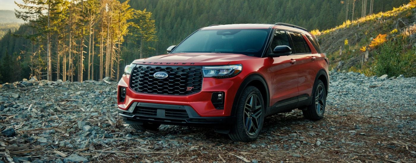 Red 2026 Ford Explorer parked on a rocky flat area in the woods.