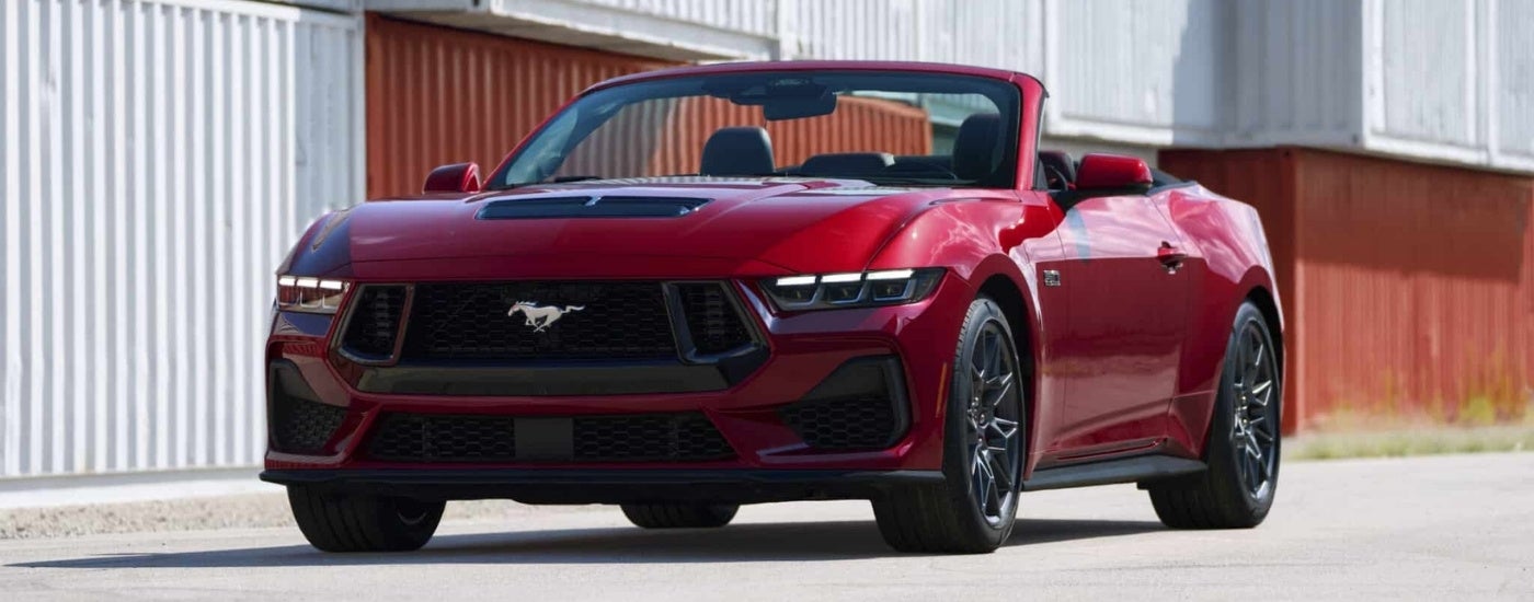 A red 2024 Ford Mustang GT parked near shipping containers.