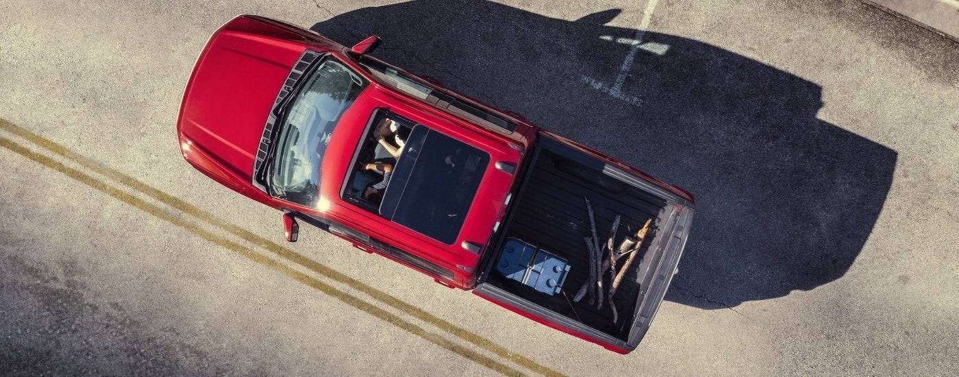 A red 2025 Ford F-150 Lightning driving on a city street.