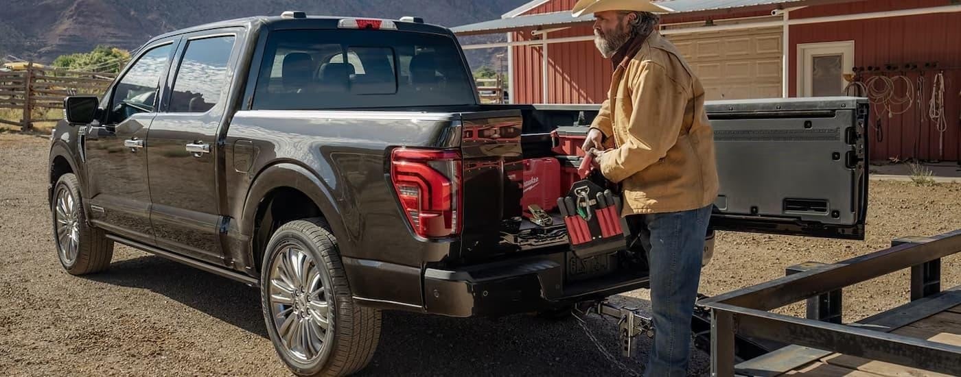Man using a saw on the back of a grey 2025 Ford F-150 near a Ford dealer near Saginaw