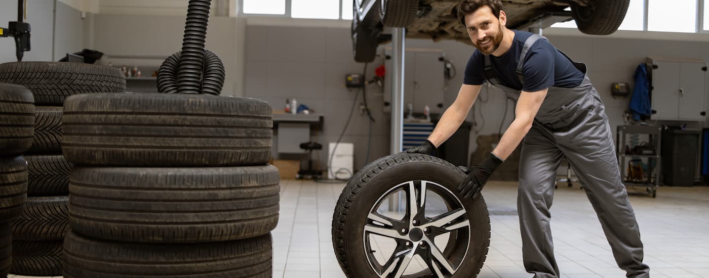 Mechanic rolling a tire in a tire shop.