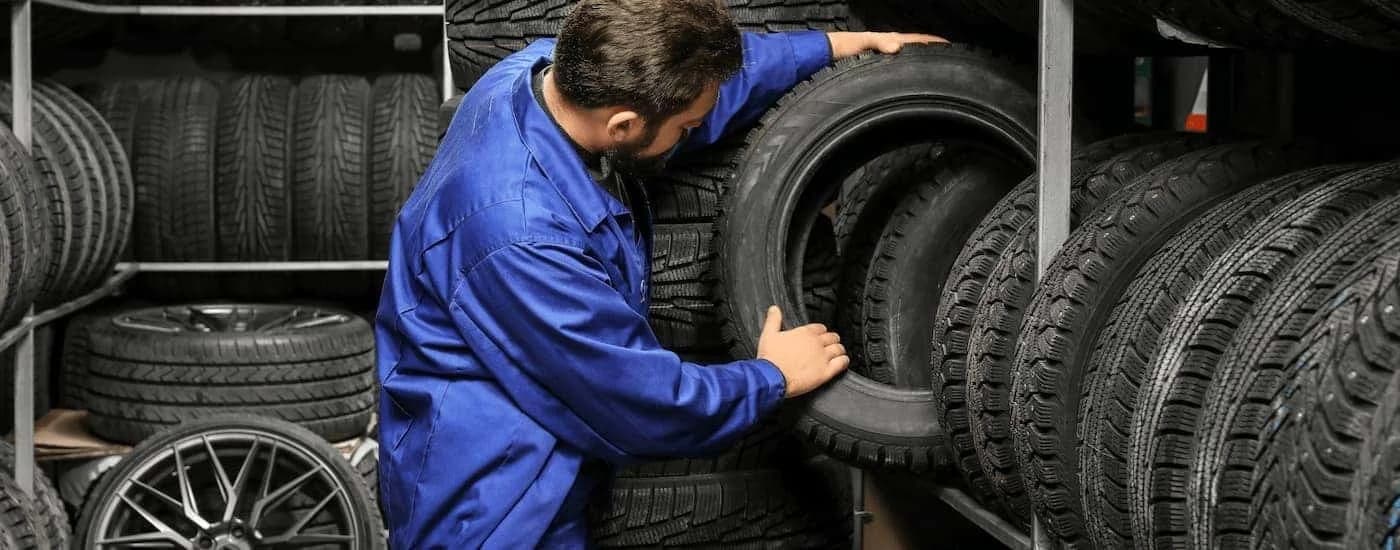 Mechanic pulling a tire off a rack.
