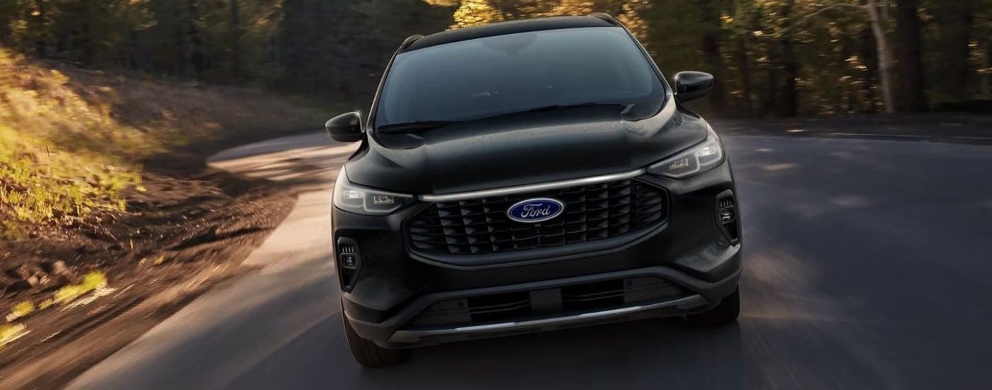 A black 2024 Ford Escape driving down a rural road